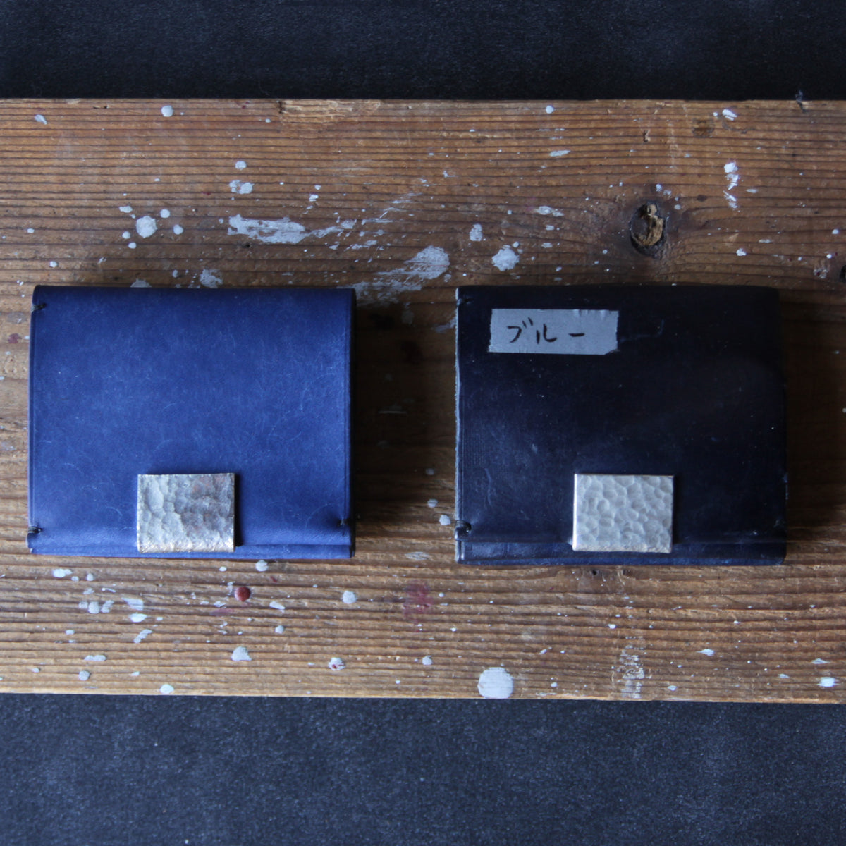 A blue wallet with tin details. Unused on the left; used for three years on the right.
