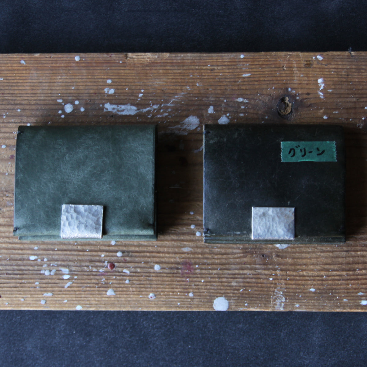 A green wallet with tin details. Unused on the left; used for three years on the right.